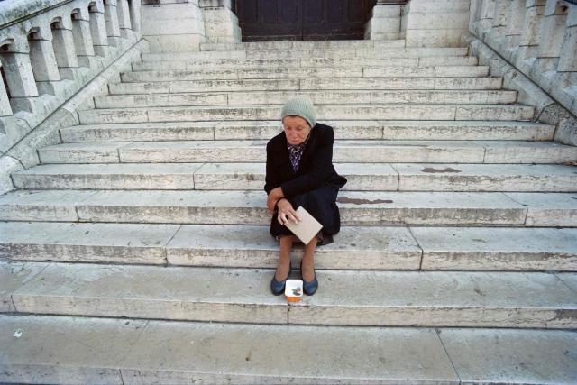 TOPSHOT - An elderly woman comes begging on the steps of the Sacrй-Cњur, on August 20, 1988, in the tourist district of Montmartre, in Paris’s 18th arrondissement. (Photo by AFP)