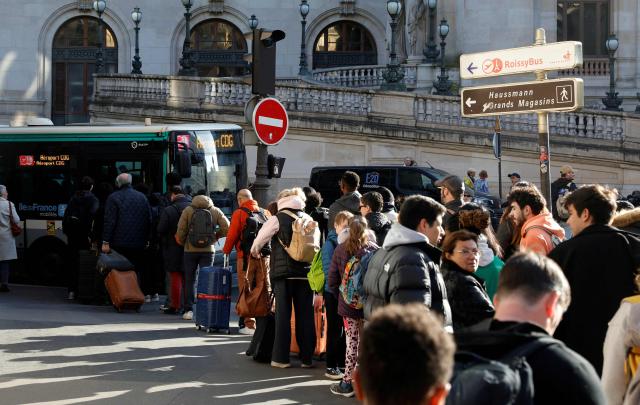 (FILES) Passengers queue to take a bus from Opera district, in order to reach Paris Charles-de-Gaulle Airport (CDG), as train traffic has been stopped at the Gare du Nord station in Paris on March 7, 2025, following the discovery of a World War II bomb. (Photo by GEOFFROY VAN DER HASSELT / AFP)