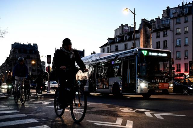 (FILES) People ride bikes and a RATP bus drives down a boulevard in central Paris early morning on December 10, 2019 on a sixth day of massive strike action over government's plans to overhaul the pension system.  (Photo by Philippe LOPEZ / AFP)