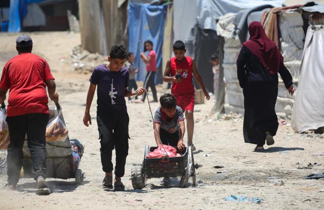 Palestinian youths push a cart amid makeshift shelters on a hot day in Gaza’s Nuseirat refugee camp on June 11, 2026. Discussions between Palestinian factions and mediators in Cairo aimed at reaching a permanent end to the war in Gaza have stalled over the pivotal question of disarming the territory and Hamas, Palestinian sources told AFP on June 9. (Photo by Eyad Baba / AFP)
