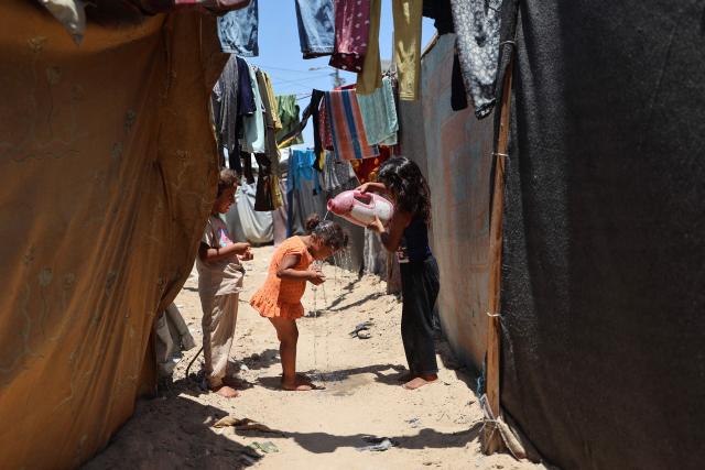 A Palestinian girl cools off with water amid makeshift shelters on a hot day in Gaza’s Nuseirat refugee camp on June 11, 2026. Discussions between Palestinian factions and mediators in Cairo aimed at reaching a permanent end to the war in Gaza have stalled over the pivotal question of disarming the territory and Hamas, Palestinian sources told AFP on June 9. (Photo by Eyad Baba / AFP)