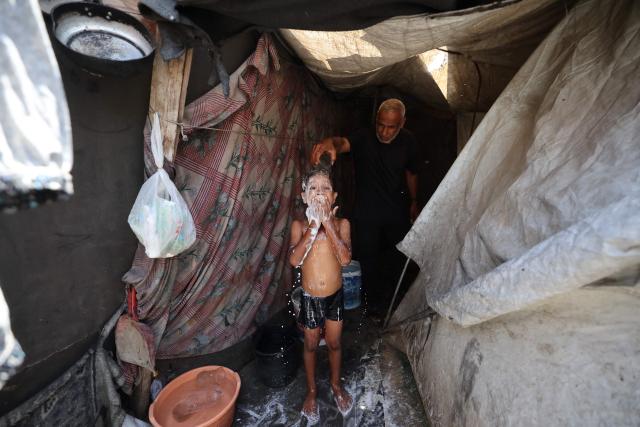 A Palestinian boy washes himself in a makeshift shelter at Gaza’s Nuseirat refugee camp on June 11, 2026. Discussions between Palestinian factions and mediators in Cairo aimed at reaching a permanent end to the war in Gaza have stalled over the pivotal question of disarming the territory and Hamas, Palestinian sources told AFP on June 9. (Photo by Eyad Baba / AFP)