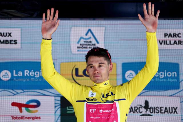 EF Education - EasyPost's French rider Alex Baudin celebrates wearing the overall leader's yellow jersey on the podium of the 5th stage of the Tour Auvergne-Rhone-Alpes cycling race (formerly known as the Criterium du Dauphine), 195,8km between Saint-Chamond and Villars-les-Dombes, central France, on June 11, 2026. (Photo by Anne-Christine POUJOULAT / AFP)