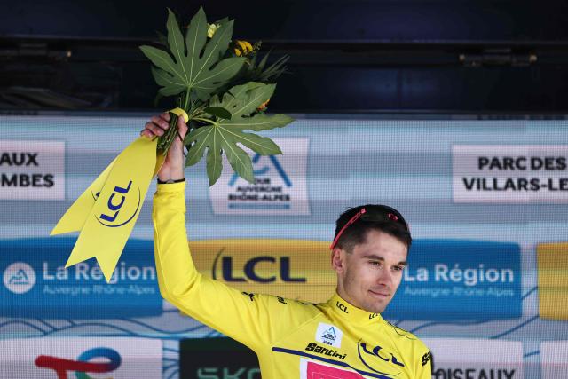 EF Education - EasyPost's French rider Alex Baudin celebrates wearing the overall leader's yellow jersey on the podium of the 5th stage of the Tour Auvergne-Rhone-Alpes cycling race (formerly known as the Criterium du Dauphine), 195,8km between Saint-Chamond and Villars-les-Dombes, central France, on June 11, 2026. (Photo by Anne-Christine POUJOULAT / AFP)
