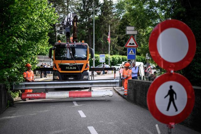 Workers install a baracade to close the border crossing between Hermance in Switzerland and Chens sur Leman in France, ahead of the upcoming G7 summit in nearby Evian, in Hermance, on June 11, 2026. The closure of 21 of the 28 border crossings between the canton of Geneva and France ahead of the G7 summit is creating a headache for cross-border commuters. (Photo by Fabrice COFFRINI / AFP)