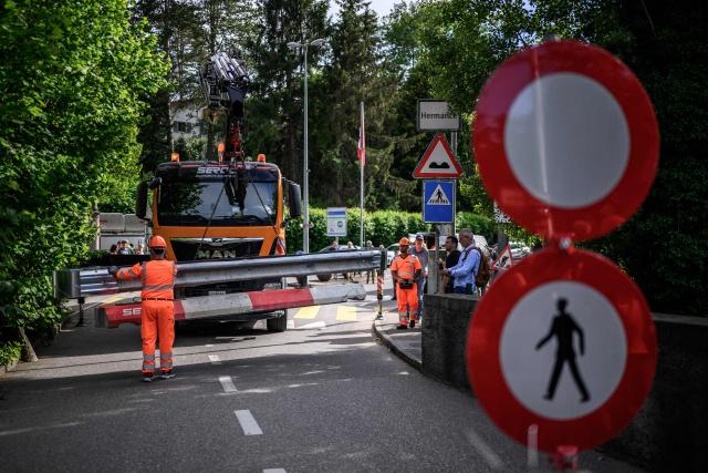 Workers install a baracade to close the border crossing between Hermance in Switzerland and Chens sur Leman in France, ahead of the upcoming G7 summit in nearby Evian, in Hermance, on June 11, 2026. The closure of 21 of the 28 border crossings between the canton of Geneva and France ahead of the G7 summit is creating a headache for cross-border commuters. (Photo by Fabrice COFFRINI / AFP)