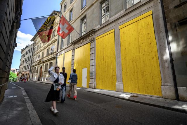 Passers-by walk past an official building with its windows boarded up with wooden panels to protect the facade ahead of demonstrations against the Evian G7 summit in Geneva on June 11, 2026. Protests against the G7 summit in Evian are set to take place in nearby Geneva, where activists can gather more easily than in the tightly secured host town. (Photo by Fabrice COFFRINI / AFP)