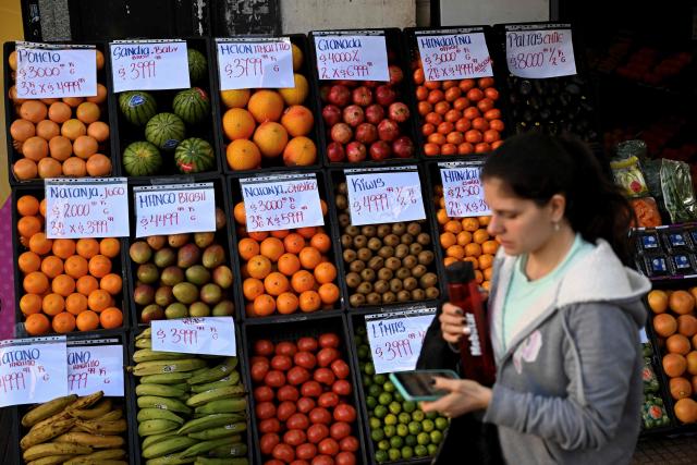 A woman passes by a fruit and vegetable stand displaying prices in Buenos Aires on June 11, 2026. (Photo by Luis ROBAYO / AFP)