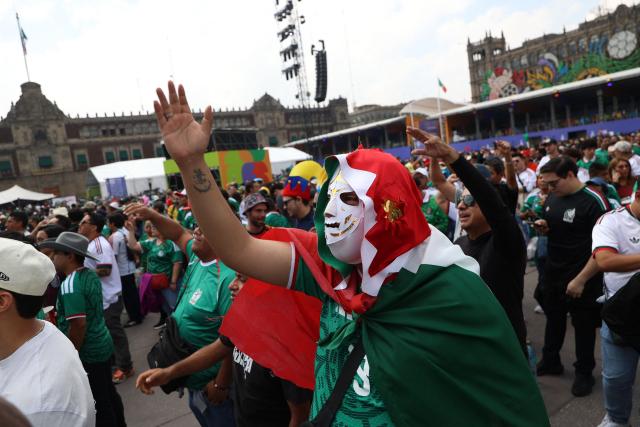 A Mexican fan wearing a lucha libre mask and draped in a Mexican flag cheers at the FIFA Fan Festival at Zocalo square ahead of the 2026 World Cup football tournament Group A match between Mexico and South Africa in Mexico City on June 11, 2026. (Photo by LUIS CORTES / AFP)