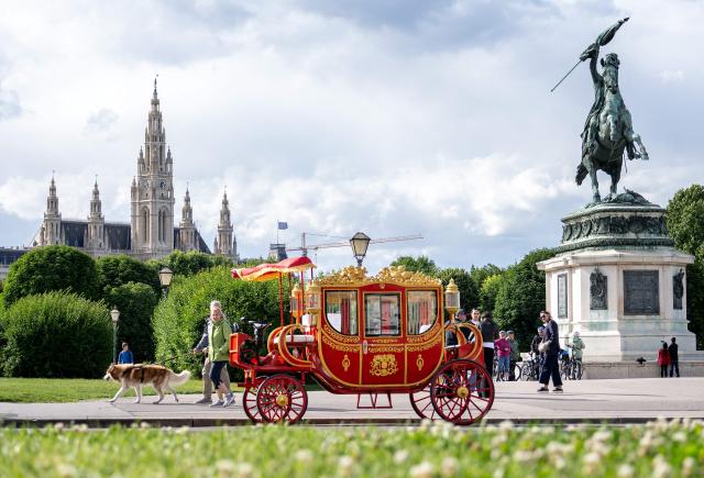 Pedestrians walk past an electric powered tourist sightseeing vehicle, made in retro imperial carriage style, parked outside the Hofburg palace in Vienna, on June 11, 2026. (Photo by Joe Klamar / AFP)