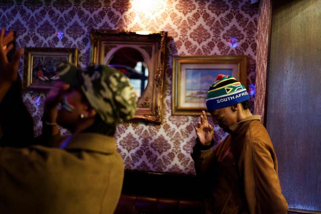 South African football supporters react and cheer during the national anthem as they watch the live broadcast of the opening football match of the 2026 FIFA World Cup between Mexico and South Africa, at Kitcheners in Braamfontein, in Johannesburg, on June 11, 2026. (Photo by WIKUS DE WET / AFP)