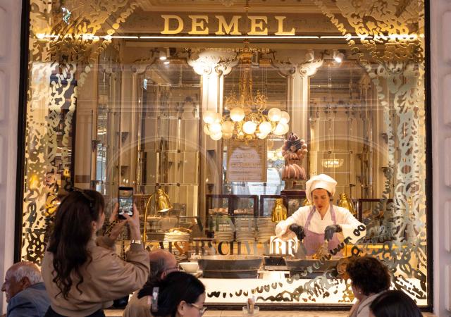 People watch through a window of the Demel restaurant a chef preparing the Kaiserschmarrn pancakes, in Vienna, on June 11, 2026. Kaiserschmarrn or Kaiserschmarren is a lightly sweetened pancake that takes its name from the Austrian emperor Franz Joseph I, who was fond of this fluffy shredded pancake. It is served as a dessert or as a light lunch. (Photo by Joe Klamar / AFP)