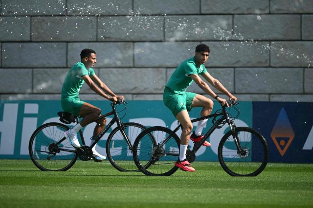 Morocco's defender Achraf Hakimi (R) rides a bike as he arrives for a training session during the 2026 World Cup football tournament at the Pingry School in Basking Ridge, New Jersey, on June 11, 2026. (Photo by MAURO PIMENTEL / AFP)