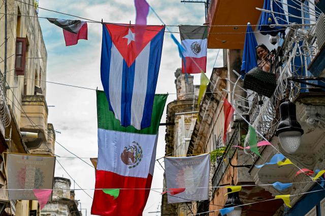 A woman look from a balcony on a street decorated with flags of Mexico and Cuba in Havana on June 11, 2026, during the World Cup opening match between Mexico and South Africa. (Photo by YAMIL LAGE / AFP)
