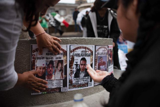 Relatives of missing persons and members of search collectives stick photos of their loved ones during a protest during the opening of the FIFA World Cup 2026 in downtown Guadalajara, Jalisco state, Mexico, on June 11, 2026. (Photo by RUTH ROSAS / AFP)