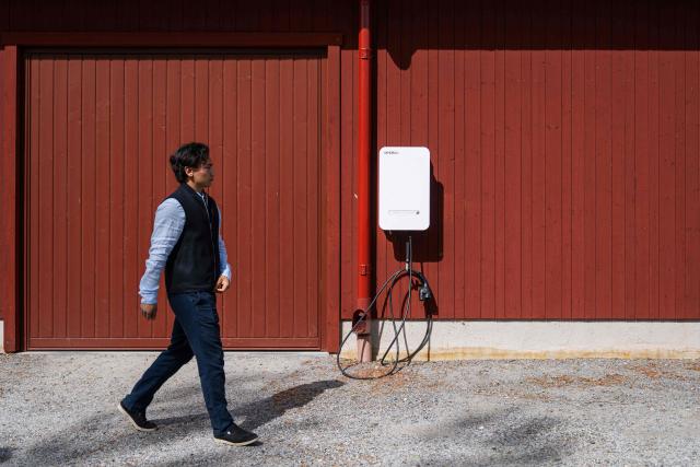 Herbert Svensson walks next to a bi-directional Vehicle-to-Grid (V2G) charging station at the BRF Stenberg condominium association on May 28, 2026, in Hudiksvall, Sweden. The residential pilot project uses Vehicle-to-Grid (V2G) technology, enabling electric vehicles to act as mobile energy storage units capable of supplying electricity back to the local grid when needed. (Photo by Jonathan NACKSTRAND / AFP)
