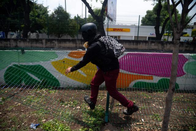 A protester takes dopwn a fence during a demo by the National Coordination of Education Workers (CNTE) near the Ciudad de Mexico Stadium in Mexico City on June 11, 2026, the opening day of the 2026 World Cup. (Photo by Marco González / AFP)