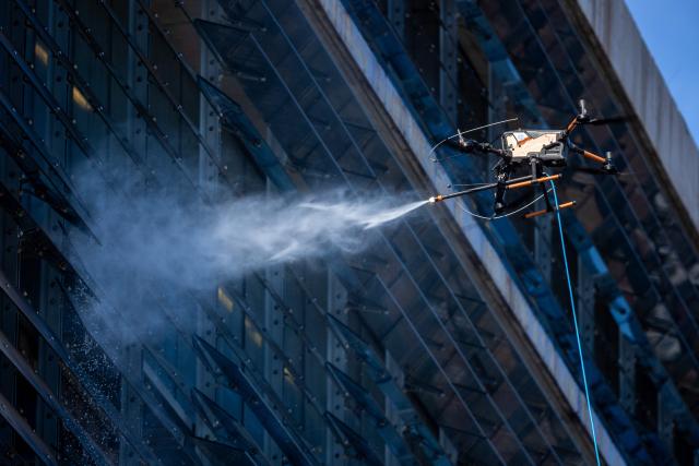 View of a drone cleaning a large building facade in Santiago, on June 11, 2026. A group of Chilean entrepreneurs created a company that uses drones to clean buildings, high-voltage towers, solar panels, and large elevated surfaces (Photo by Raul BRAVO / AFP)