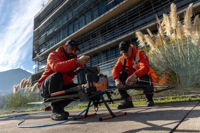 Employees prepare a drone to clean a large building facade in Santiago, on June 11, 2026. A group of Chilean entrepreneurs created a company that uses drones to clean buildings, high-voltage towers, solar panels, and large elevated surfaces (Photo by Raul BRAVO / AFP)