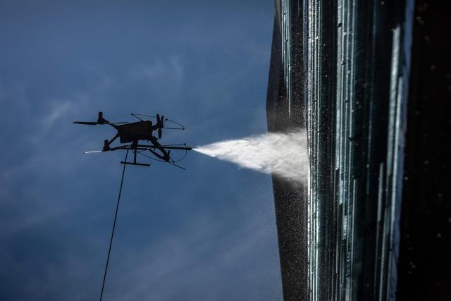 View of a drone cleaning a large building facade in Santiago, on June 11, 2026. A group of Chilean entrepreneurs created a company that uses drones to clean buildings, high-voltage towers, solar panels, and large elevated surfaces (Photo by Raul BRAVO / AFP)