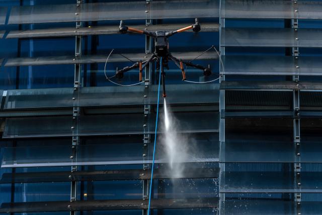 View of a drone cleaning a large building facade in Santiago, on June 11, 2026. A group of Chilean entrepreneurs created a company that uses drones to clean buildings, high-voltage towers, solar panels, and large elevated surfaces (Photo by Raul BRAVO / AFP)