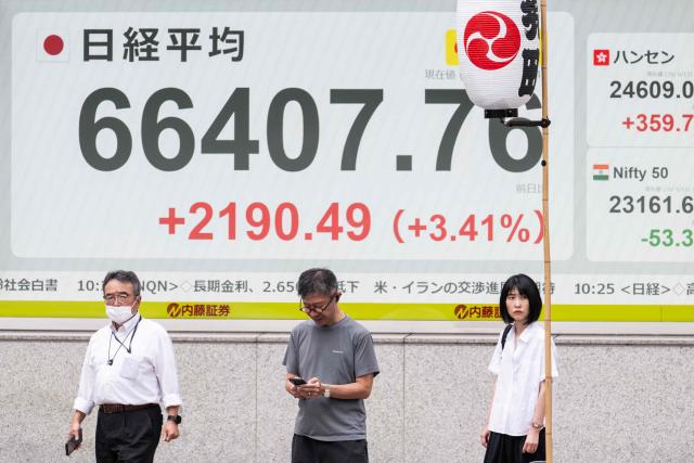 People stand in front of a board showing the current levels of the Tokyo Stock Exchange along a street in Tokyo on June 12, 2026. Japan's Nikkei share index soared more than four percent on June 12 after US President Donald Trump withdrew his threat of further strikes against Iran and said a deal to end the war could be signed in coming days. (Photo by Andrew CABALLERO-REYNOLDS / AFP)