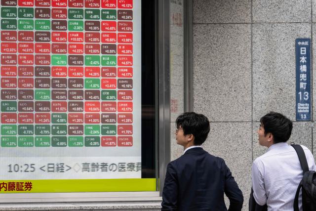 Two men look at an electronic quotation board displaying the Nikkei 225 stock prices on the Tokyo Stock Exchange  in Tokyo on June 12, 2026. Japan's Nikkei share index soared more than four percent on June 12 after US President Donald Trump withdrew his threat of further strikes against Iran and said a deal to end the war could be signed in coming days. (Photo by Andrew CABALLERO-REYNOLDS / AFP)