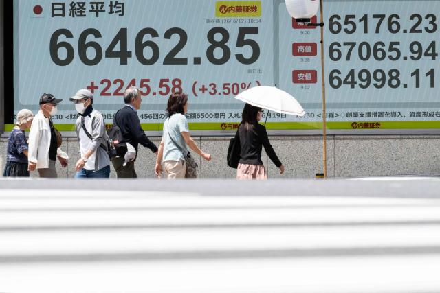 People pass a board showing the current levels of the Tokyo Stock Exchange along a street in Tokyo on June 12, 2026. Japan's Nikkei share index soared more than four percent on June 12 after US President Donald Trump withdrew his threat of further strikes against Iran and said a deal to end the war could be signed in coming days. (Photo by Andrew CABALLERO-REYNOLDS / AFP)