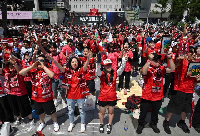South Korean fans cheer as they watch the 2026 World Cup football match between South Korea and the Czech Republic on big screens in Seoul on June 12, 2026. (Photo by Jung Yeon-je / AFP)