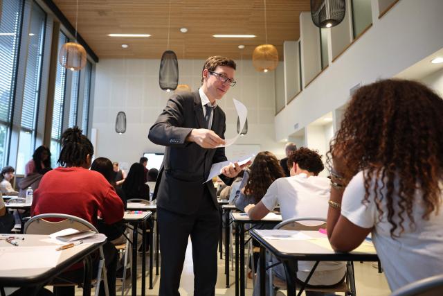 France's Education Minister Edouard Geffray (C) delivers to students their mathematics exam paper as part of the baccalaureate exam during his visit at the Gabriel Faure school and middle school in Paris on June 12, 2026. (Photo by SIMON WOHLFAHRT / POOL / AFP)