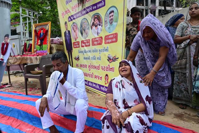 The mother (bottom R) of Air India Flight 171 plane crash victim Akash Patni grieves at the crash site on the first anniversary of the disaster in Ahmedabad on June 12, 2026. India's aviation accident probe agency is facing renewed criticism from pilot groups ahead of the anniversary of the 2025 Air India Boeing-787 crash in Ahmedabad, which killed 260 people. (Photo by Shammi MEHRA / AFP)