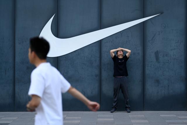 A man stretches outside a Nike store in Beijing on June 12, 2026. (Photo by WANG Zhao / AFP)