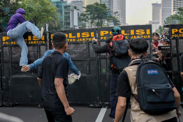 Students and police officers clash while demonstrating to demand a reduction in fuel prices and the dissolution of the free meal program, which they consider to be a hotbed of corruption, in Jakarta on June 12, 2026. (Photo by BAY ISMOYO / AFP)