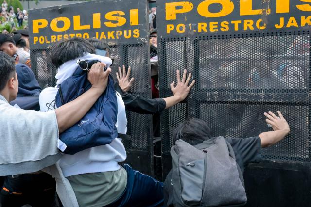 Students and police officers clash while demonstrating to demand a reduction in fuel prices and the dissolution of the free meal program, which they consider to be a hotbed of corruption, in Jakarta on June 12, 2026. (Photo by BAY ISMOYO / AFP)