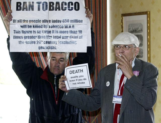 (FILES) Anti-smoking campaigner Stuart Holmes (L) interrupts a photo-call by British artist and pro-smoking campaigner David Hockney at the Labour Party Conference in Brighton 28 September 2005. British artist David Hockney, considered one of the most influential and defining figures in contemporary art, whose paintings captured the world in brilliant colour, has died aged 88, his public relations agent announced on June 12, 2026. (Photo by ALESSANDRO ABBONIZIO / AFP)