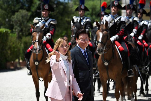 Italy's Prime Minister Giorgia Meloni (L)  welcomes South Korea's President Lee Jae Myung as they review the guards of honour, prior to a bilateral meeting at Villa Doria Pamphili, in Rome on June 12, 2026. (Photo by Andreas SOLARO / AFP)