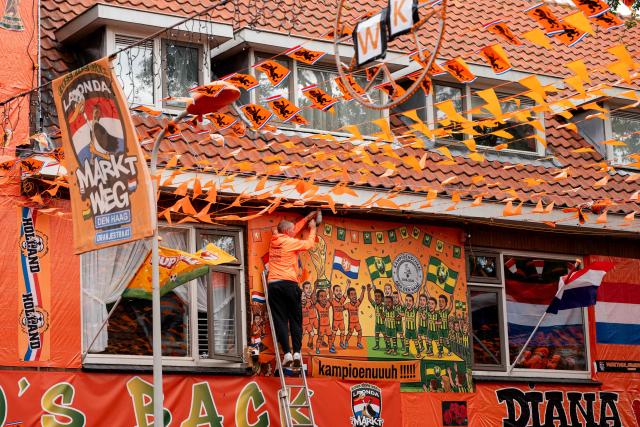 A man works in the Marktweg street, decorated and renamed "Oranjestraat" (orange street) by its residents during the 2026 FIFA World Cup football tournament in The Hague on June 12, 2026. The Netherlands will open its 2026 FIFA World Cup Group F campaign co-hosted by the United States, Mexico and Canada, against Japan at the AT&T Stadium in Arlington on June 14, 2026. (Photo by Lina Selg / AFP)