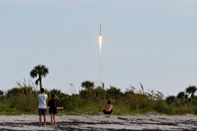 People watch as a SpaceX Falcon 9 rocket carrying the Starlink 10-54 mission lifts off from Space Launch Complex 40 at Cape Canaveral Space Force Station in Cape Canaveral, Florida, on June 12, 2026. Elon Musk's SpaceX begins trading on the Nasdaq exchange on Friday with the biggest initial public offering in history expected to make the polarizing entrepreneur the world's first trillionaire. The company priced more than 555 million shares at $135 each in a filing with the US markets regulator on Thursday, placing SpaceX in the top 10 of Wall Street's biggest companies with a valuation of just under $1.8 trillion -- ahead of Tesla, Facebook-owner Meta and Walmart. (Photo by CHANDAN KHANNA / AFP)