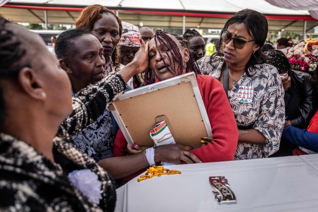 A relative mourns as she hugs a portrait of a victim of the Utumishi Girls' Academy Senior School fire while being comforted by others in front of a coffin during a memorial mass amid growing concern over a wave of school fires across Kenya at Gilgil Stadium in Gilgil, on June 12, 2026. The blaze at Utumishi Girls Academy last month left 16 schoolgirls dead and 132 injured, according to the Kenya Red Cross, one of 47 fires that have broken out across the country this year.The spate of school fires has provoked a national conversation, and raised urgent political questions.But at Gilgil Stadium, in Nakuru County about 120 kilometres (75 miles) north of Nairobi, spiritual leaders steered the conversation away from political questions. (Photo by Luis TATO / AFP)