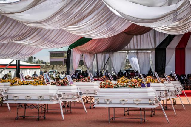 A general view shows the coffins of victims of the Utumishi Girls' Academy Senior School as mourners pray during a memorial mass amid growing concern over a wave of school fires across Kenya at Gilgil Stadium in Gilgil, on June 12, 2026. The blaze at Utumishi Girls Academy last month left 16 schoolgirls dead and 132 injured, according to the Kenya Red Cross, one of 47 fires that have broken out across the country this year.The spate of school fires has provoked a national conversation, and raised urgent political questions.But at Gilgil Stadium, in Nakuru County about 120 kilometres (75 miles) north of Nairobi, spiritual leaders steered the conversation away from political questions. (Photo by Luis TATO / AFP)