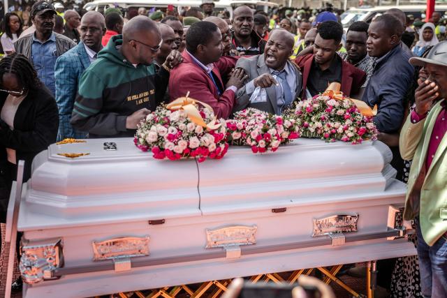 The father of a victim of the Utumishi Girls' Academy Senior School fire reacts as he is comforted by others in front of a coffin during a memorial mass amid growing concern over a wave of school fires across Kenya at Gilgil Stadium in Gilgil, on June 12, 2026. The blaze at Utumishi Girls Academy last month left 16 schoolgirls dead and 132 injured, according to the Kenya Red Cross, one of 47 fires that have broken out across the country this year.The spate of school fires has provoked a national conversation, and raised urgent political questions.But at Gilgil Stadium, in Nakuru County about 120 kilometres (75 miles) north of Nairobi, spiritual leaders steered the conversation away from political questions. (Photo by Luis TATO / AFP)
