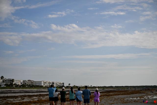 People watch as a SpaceX Falcon 9 rocket carrying the Starlink 10-54 mission lifts off from Space Launch Complex 40 at Cape Canaveral Space Force Station in Cape Canaveral, Florida, on June 12, 2026. Elon Musk's SpaceX begins trading on the Nasdaq exchange on Friday with the biggest initial public offering in history expected to make the polarizing entrepreneur the world's first trillionaire. The company priced more than 555 million shares at $135 each in a filing with the US markets regulator on Thursday, placing SpaceX in the top 10 of Wall Street's biggest companies with a valuation of just under $1.8 trillion -- ahead of Tesla, Facebook-owner Meta and Walmart. (Photo by CHANDAN KHANNA / AFP)