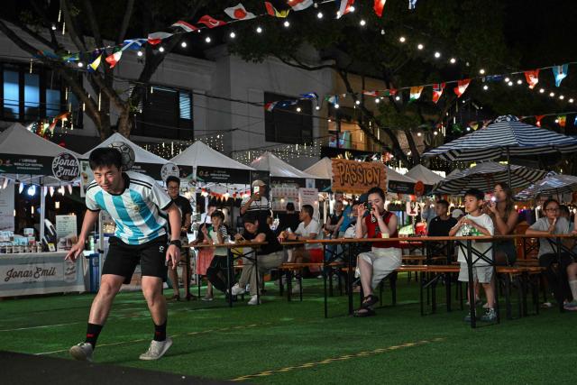 People watch a freestyle football show on a World Cup themed bar street in Shanghai on June 12, 2026. (Photo by Jade GAO / AFP)