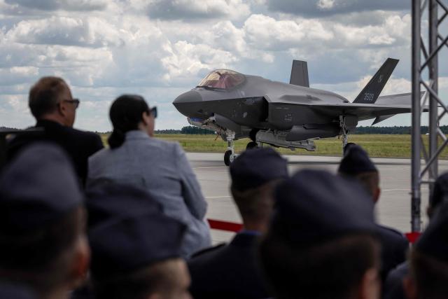 Spectators look on a US-made F-35 aircraft (Polish codename Husarz) of the Polish Air Force parked on the tarmac at the 32nd Tactical Air Base in Lask, central Poland, on June 12, 2026, on the day of their official entry into service with the Polish Air Force. (Photo by Wojtek RADWANSKI / AFP)