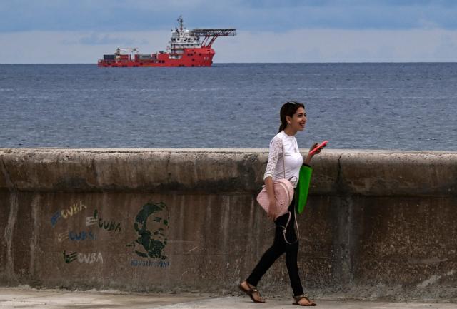 A woman walks using her mobile phone as the Colombian Navy ship ARC Caribe arrives carrying humanitarian aid in Havana, on June 12, 2026.  (Photo by YAMIL LAGE / AFP)