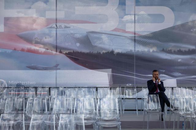 Poland's Deputy Prime Minister and Minister of Defence Wladyslaw Kosiniak Kamysz talks sits among empty chairs and talks on his mobile phone after the ceremony for the official entry into service with the Polish Air Force of the first tree US-made F-35 aircrafts (Polish codename Husarz) on June 12, 2026, at the 32nd Tactical Air Base in Lask, central Poland. (Photo by Wojtek RADWANSKI / AFP)