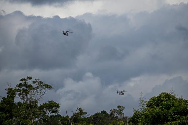 Venezuelan army helicopters fly over Las Brisas de Cuyuni, as seen from an artisanal gold mine near the town of Las Claritas in Bolivar state, Venezuela, during a security operation on June 11, 2026. Venezuela, home to the world's largest oil reserves, also has deposits of gold, diamonds, bauxite, coltan and rare earths, but much of its mining areas — notably the 112,000 sq km Mining Arc located in remote regions far from major cities — is controlled by armed gangs or guerrilla groups. (Photo by Federico PARRA / AFP)