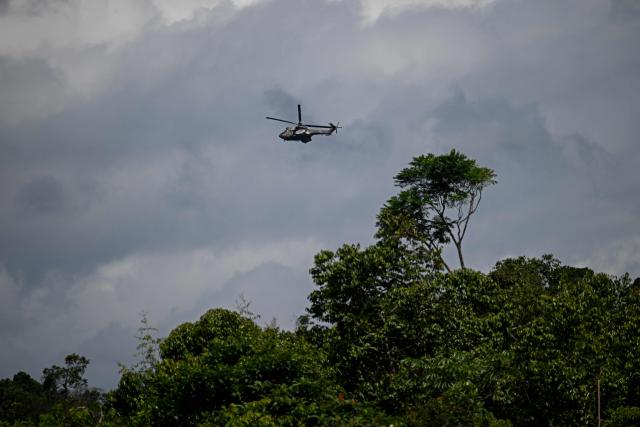 A Venezuelan army helicopter flies over Las Brisas de Cuyuni, as seen from an artisanal gold mine near the town of Las Claritas in Bolivar state, Venezuela, during a security operation on June 11, 2026. Venezuela, home to the world's largest oil reserves, also has deposits of gold, diamonds, bauxite, coltan and rare earths, but much of its mining areas — notably the 112,000 sq km Mining Arc located in remote regions far from major cities — is controlled by armed gangs or guerrilla groups. (Photo by Federico PARRA / AFP)