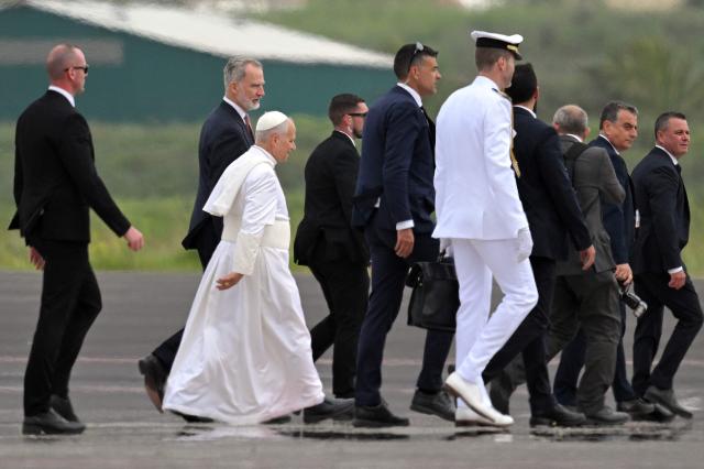 Pope Leo XIV walks to embark a new aircraft offered by Spanish King Felipe VI (2L) after his first plane's takeoff was delayed due to an incident at Los Rodeos International Airport on the Canary Island of Tenerife on June 12, 2026. Pope Leo XIV will return to Rome from the Canary Islands today on a plane offered by Spanish King Felipe VI after his orginal aircraft suffered a technical glitch, the Vatican said. The flight is scheduled to depart Tenerife at 6 pm (1700 GMT) and arrive in Rome at around 11 pm, it said in a statement. (Photo by JORGE GUERRERO / AFP)