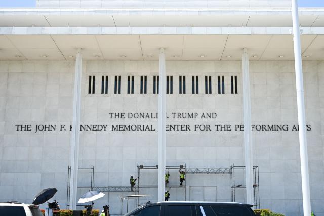 Workers stand on scaffolding near signage for the Donald J. Trump and John F. Kennedy Memorial Center for the Performing Arts in Washington, DC, on June 12, 2026. A US judge on May 29, 2026, ruled that the famed Kennedy Center for the Performing Arts had been illegally renamed after President Donald Trump and that his name must be taken down. (Photo by Alex WROBLEWSKI / AFP)